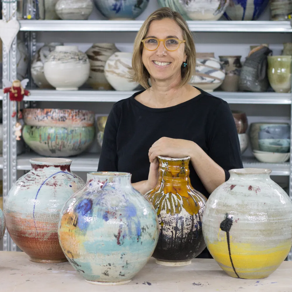 Michal Gelbard in her studio with a row of glazed vessels