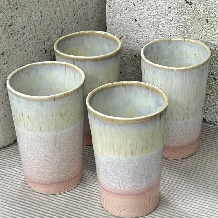 Four cream and pink cups on a striped surface