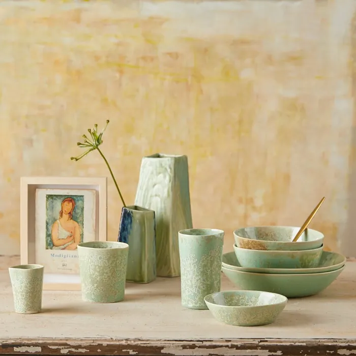 A green tableware set styled against a yellow wash