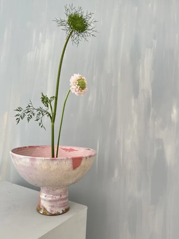 A pink footed bowl holding scabiosa and fennel