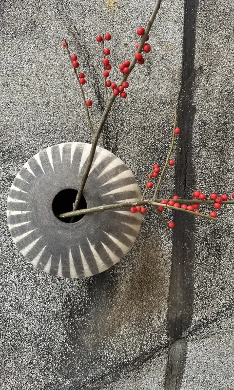 Red berry branches through a fluted vessel